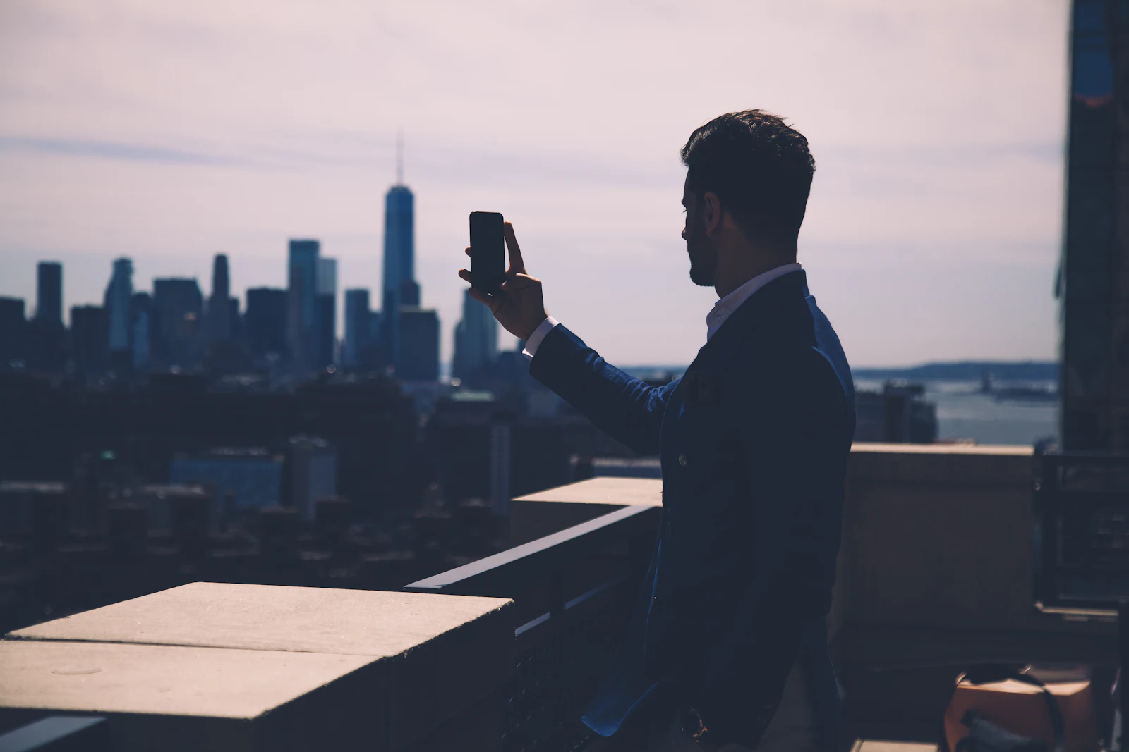 Construction executive on a rooftop looking out over the city skyline at dusk