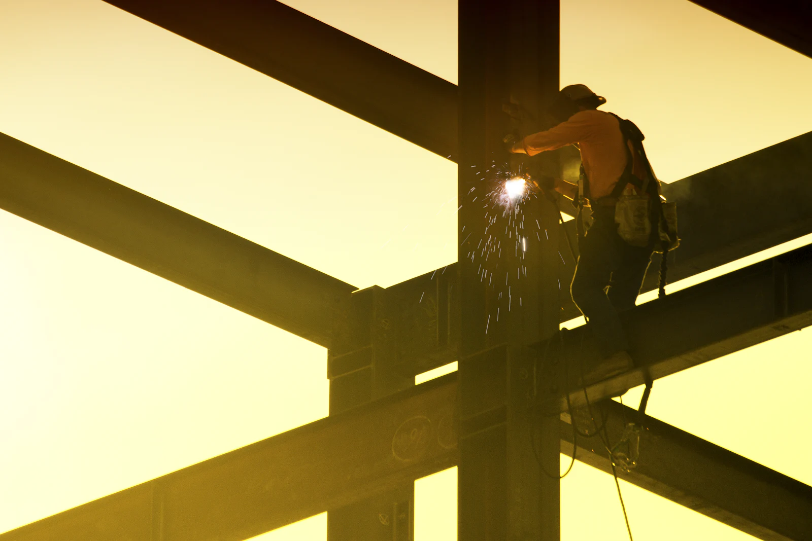 Ironworker welding structural steel at sunset